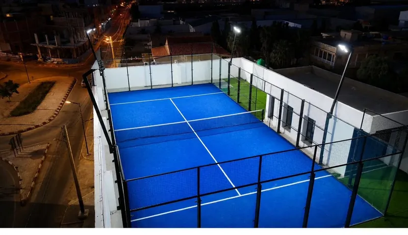 Court Pro Padel illuminé la nuit, vue aérienne sur la ville